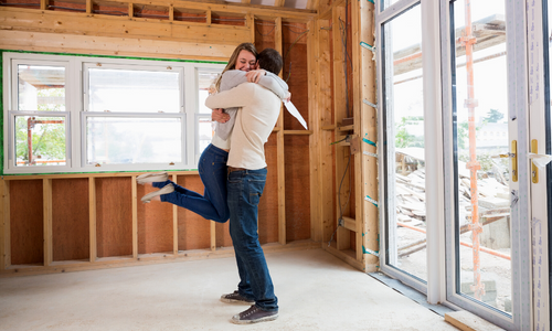 Couple hugging in house being built